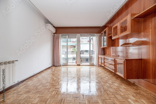 Living room with white aluminum radiators, air conditioning unit, wooden bookcase mural on one wall and oak parquet flooring