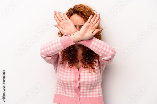 Young ginger caucasian woman isolated on white background keeping two arms crossed, denial concept.