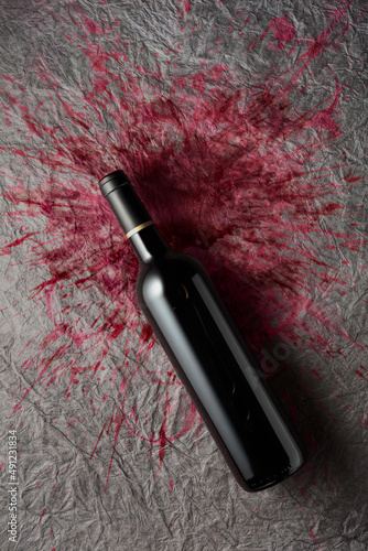 Bottle of red wine on a paper background with stains of wine.