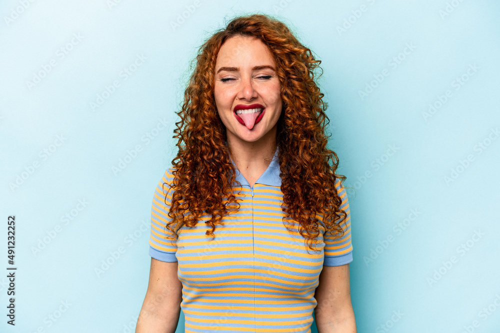 Young ginger caucasian woman isolated on blue background funny and friendly sticking out tongue. Young ginger caucasian woman isolated on blue background funny and friendly sticking out tongue.