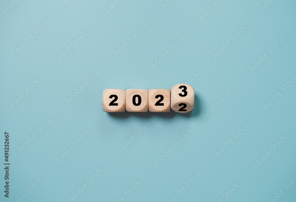Wooden cube block flipping from 2022 to 2023 on blue background , preparation for merry Christmas and happy new yea concept. Wooden cube block flipping from 2022 to 2023 on blue background , preparation for merry Christmas and happy new yea concept.