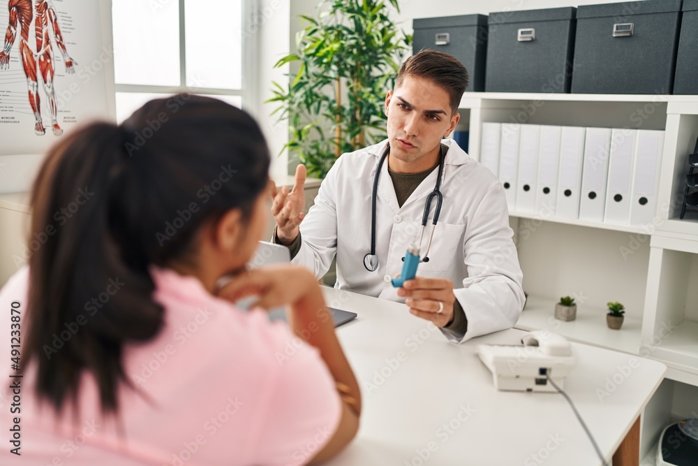 Man and woman doctor and patient having medical consultation holding inhaler at clinic Man and woman doctor and patient having medical consultation holding inhaler at clinic