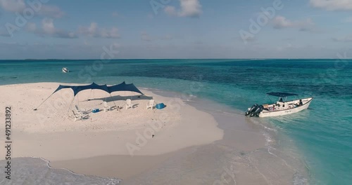 Drone turning around small Caribbean island with tent, beach cooler and boat ready to receive tourists in los Roques photo