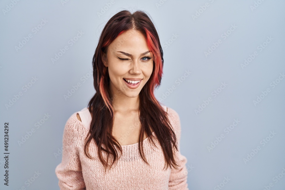 Young caucasian woman wearing pink sweater over isolated background winking looking at the camera with sexy expression, cheerful and happy face. Young caucasian woman wearing pink sweater over isolated background winking looking at the camera with sexy expression, cheerful and happy face.