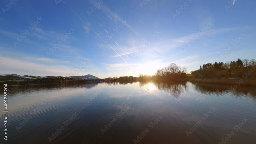 FPV drone shot low over a small lake, spring sunset in rural Bavaria, Germany FPV drone shot low over a small lake, spring sunset in rural Bavaria, Germany
