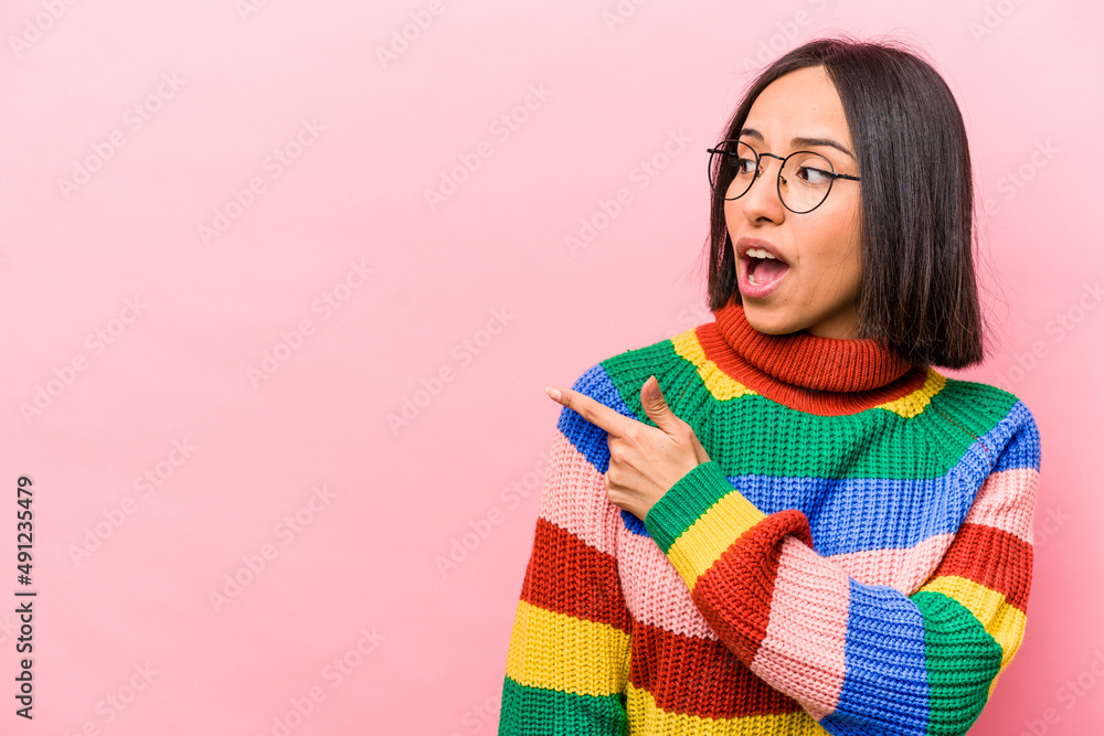 Young hispanic woman isolated on pink background points with thumb finger away, laughing and carefree. Young hispanic woman isolated on pink background points with thumb finger away, laughing and carefree.