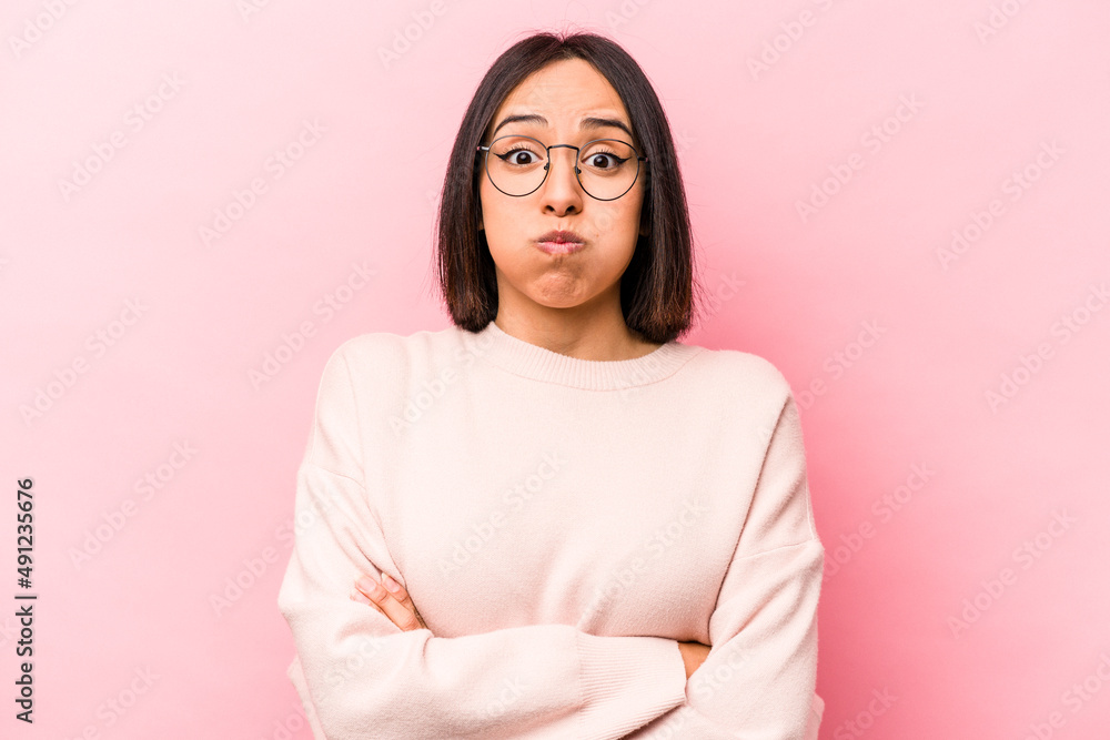 Young hispanic woman isolated on pink background blows cheeks, has tired expression. Facial expression concept. Young hispanic woman isolated on pink background blows cheeks, has tired expression. Facial expression concept.