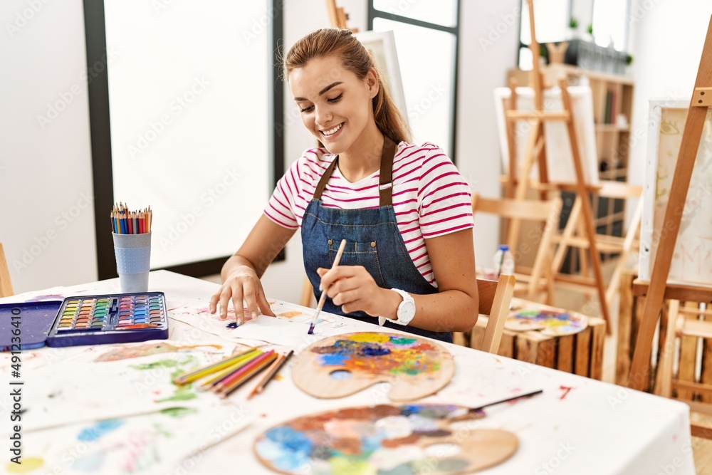 Young woman sitting on table drawing at art studio