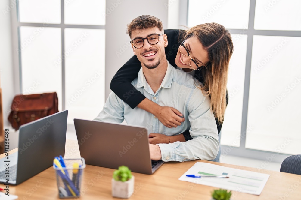 Young man and woman business workers hugging each other working at office Young man and woman business workers hugging each other working at office