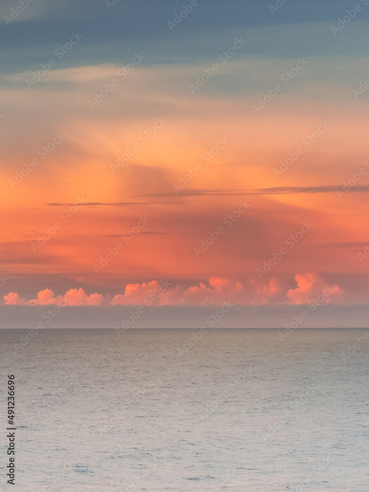 a sunset and clouds over the sea in pink and orange tones