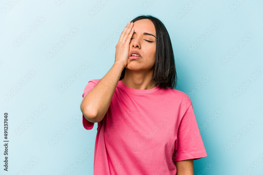 Young hispanic woman isolated on blue background tired and very sleepy keeping hand on head. Young hispanic woman isolated on blue background tired and very sleepy keeping hand on head.
