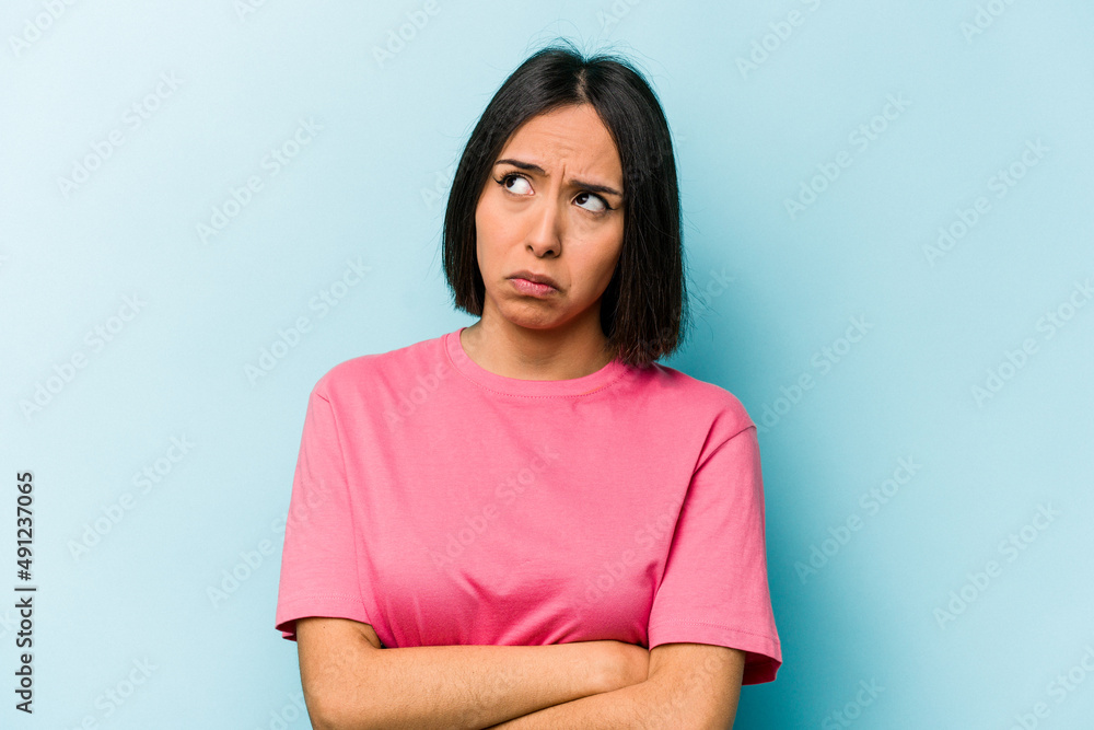 Young hispanic woman isolated on blue background tired of a repetitive task. Young hispanic woman isolated on blue background tired of a repetitive task.