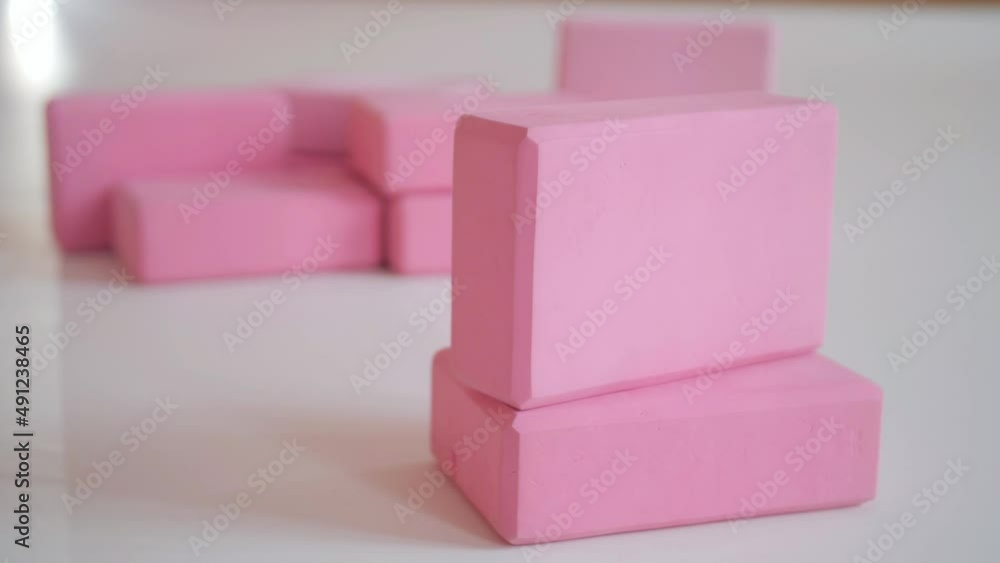 Pink yoga blocks are stacked on the floor in a yoga studio. Pink yoga blocks are stacked on the floor in a yoga studio.