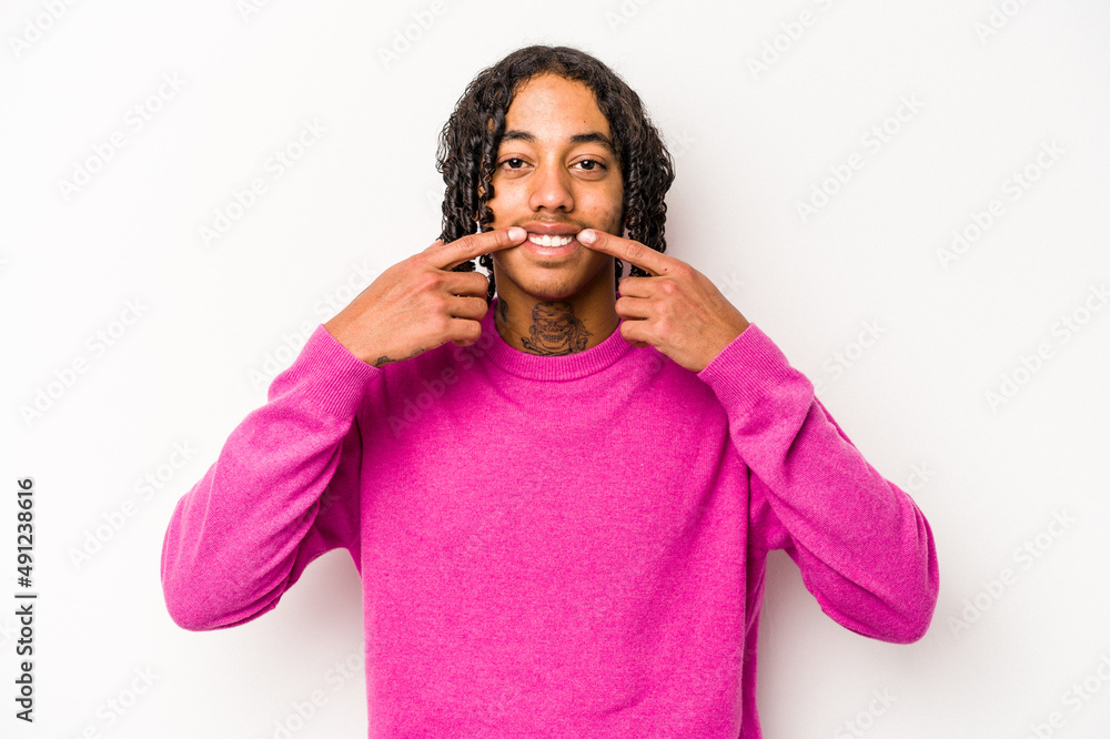 Young African American man isolated on white background smiles, pointing fingers at mouth. Young African American man isolated on white background smiles, pointing fingers at mouth.