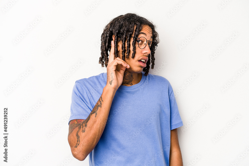 Young African American man isolated on white background trying to listening a gossip.
