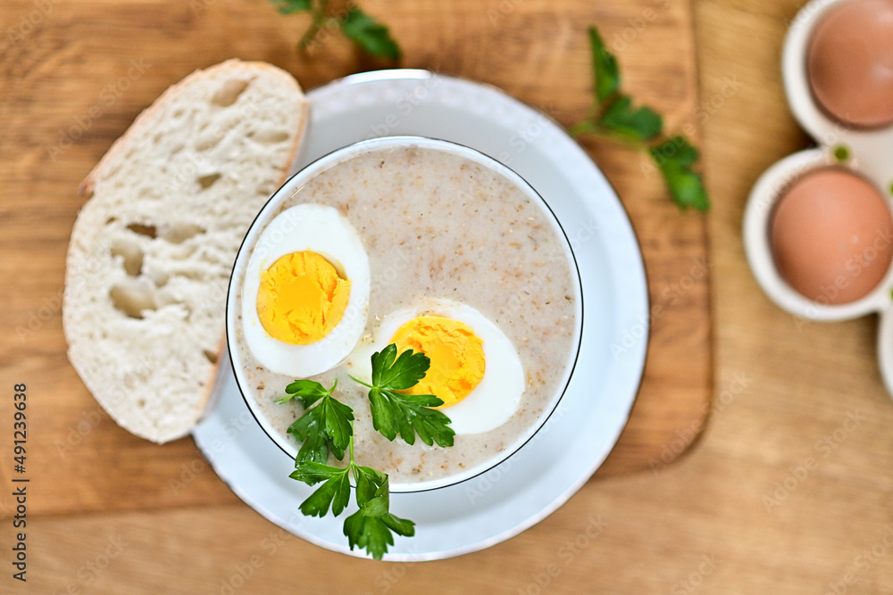 Naklejka premium Traditional Polish soup served with bread and eggs. Easter decoration. Sour soup