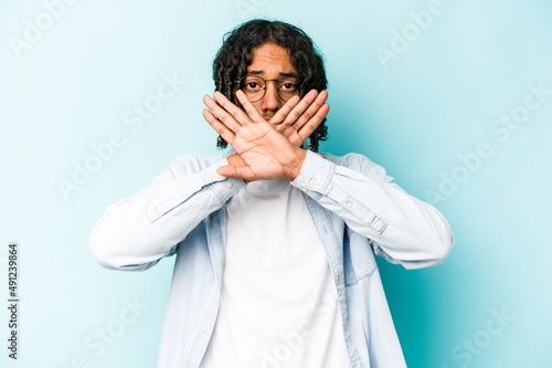 Young African American man isolated on blue background doing a denial gesture © Asier