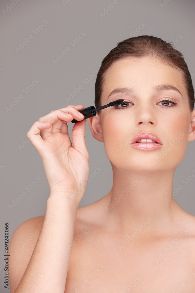 Lovely lashes. Studio portrait of a beautiful woman applying mascara.