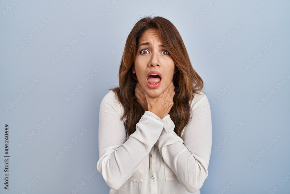 Hispanic woman standing over isolated background shouting suffocate because painful strangle. health problem. asphyxiate and suicide concept. Hispanic woman standing over isolated background shouting suffocate because painful strangle. health problem. asphyxiate and suicide concept.