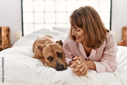 Young caucasian woman smiling confident lying on bed with dog at bedroom