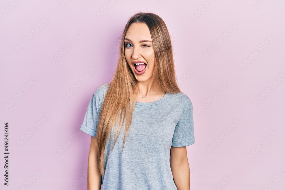 Young blonde girl wearing casual t shirt winking looking at the camera with sexy expression, cheerful and happy face. Young blonde girl wearing casual t shirt winking looking at the camera with sexy expression, cheerful and happy face.