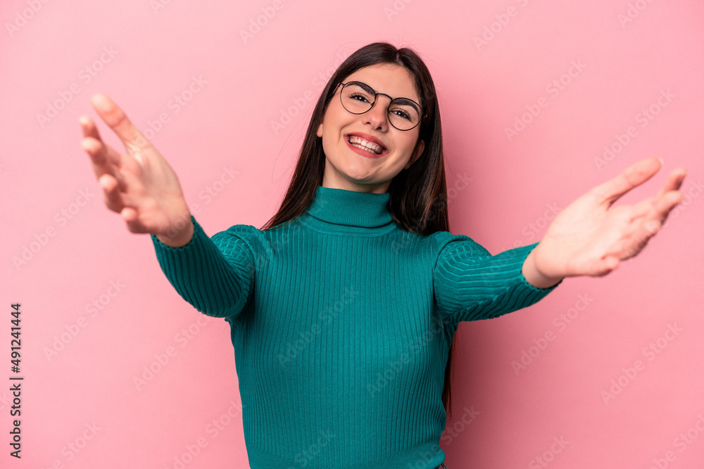 Young caucasian woman isolated on pink background feels confident giving a hug to the camera. Young caucasian woman isolated on pink background feels confident giving a hug to the camera.