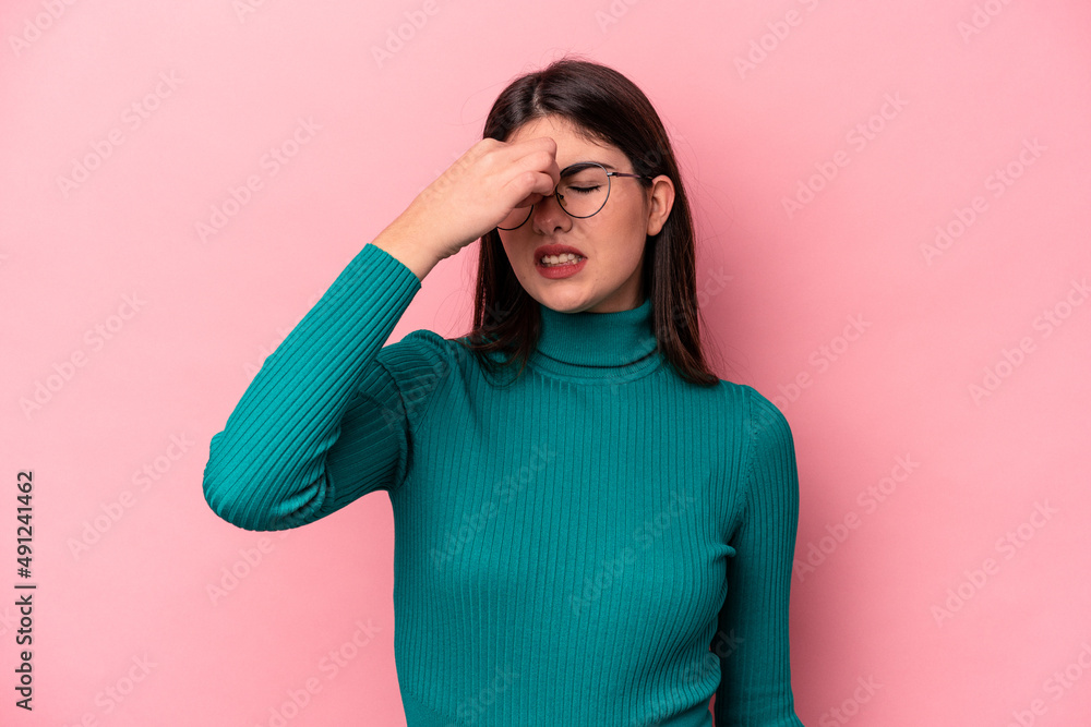 Young caucasian woman isolated on pink background having a head ache, touching front of the face. Young caucasian woman isolated on pink background having a head ache, touching front of the face.