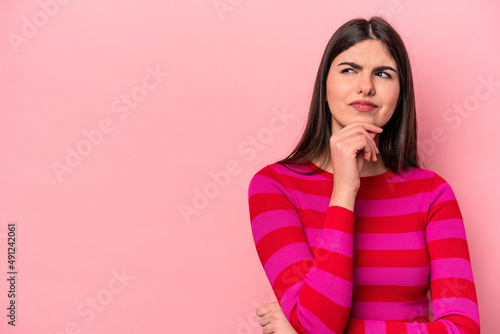 Canvastavla Young caucasian woman isolated on pink background looking sideways with doubtful and skeptical expression