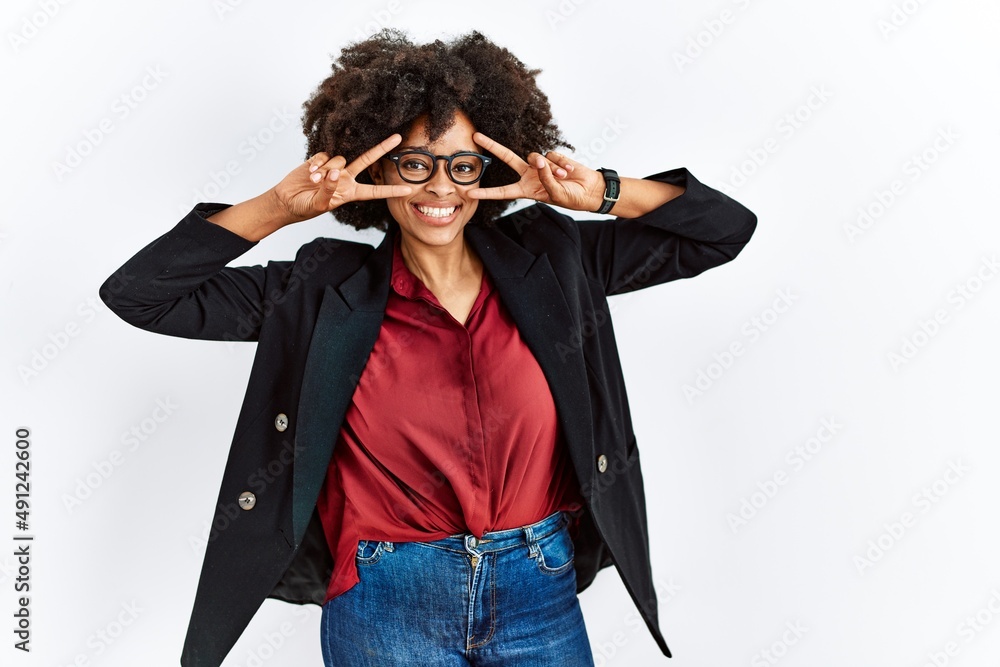 African american woman with afro hair wearing business jacket and glasses doing peace symbol with fingers over face, smiling cheerful showing victory African american woman with afro hair wearing business jacket and glasses doing peace symbol with fingers over face, smiling cheerful showing victory