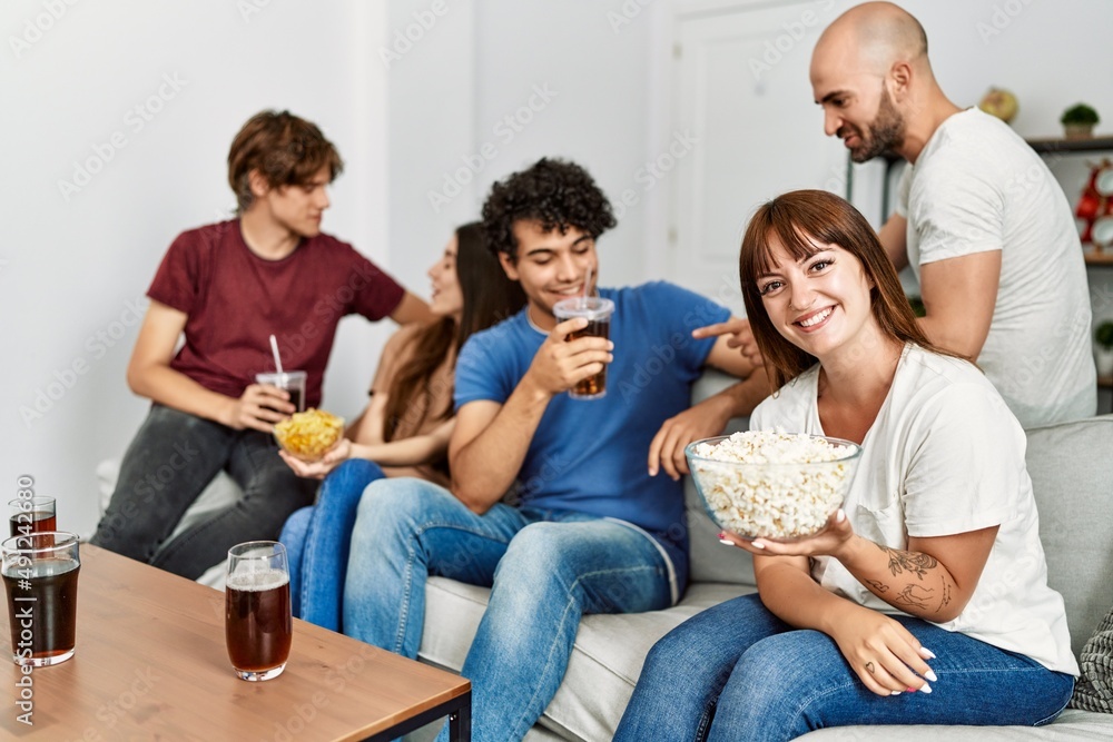 Group of young friends having party sitting on the sofa at home.