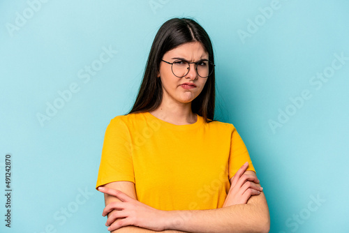 Young caucasian woman isolated on blue background unhappy looking in camera with sarcastic expression.