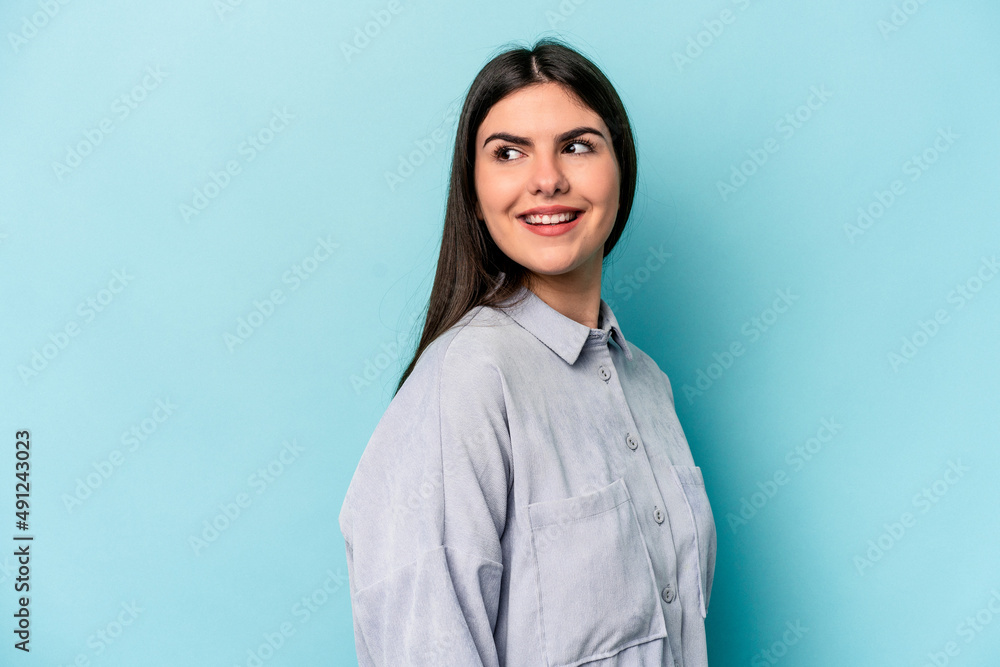 Young caucasian woman isolated on blue background looks aside smiling, cheerful and pleasant. Young caucasian woman isolated on blue background looks aside smiling, cheerful and pleasant.