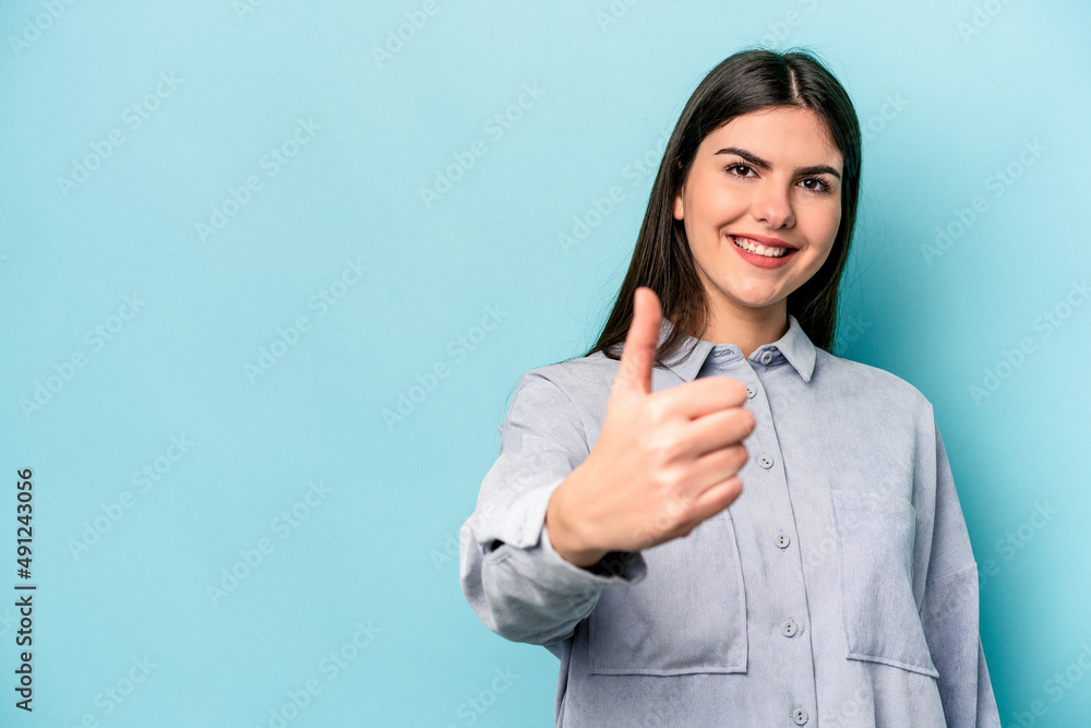 Young caucasian woman isolated on blue background smiling and raising thumb up