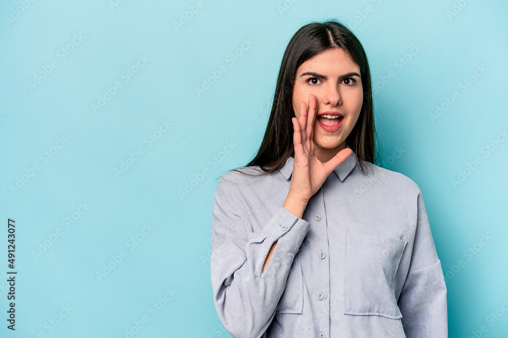Young caucasian woman isolated on blue background shouts loud, keeps eyes opened and hands tense. Young caucasian woman isolated on blue background shouts loud, keeps eyes opened and hands tense.