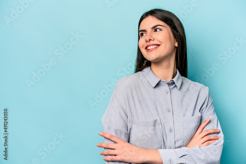 Young caucasian woman isolated on blue background smiling confident with crossed arms.