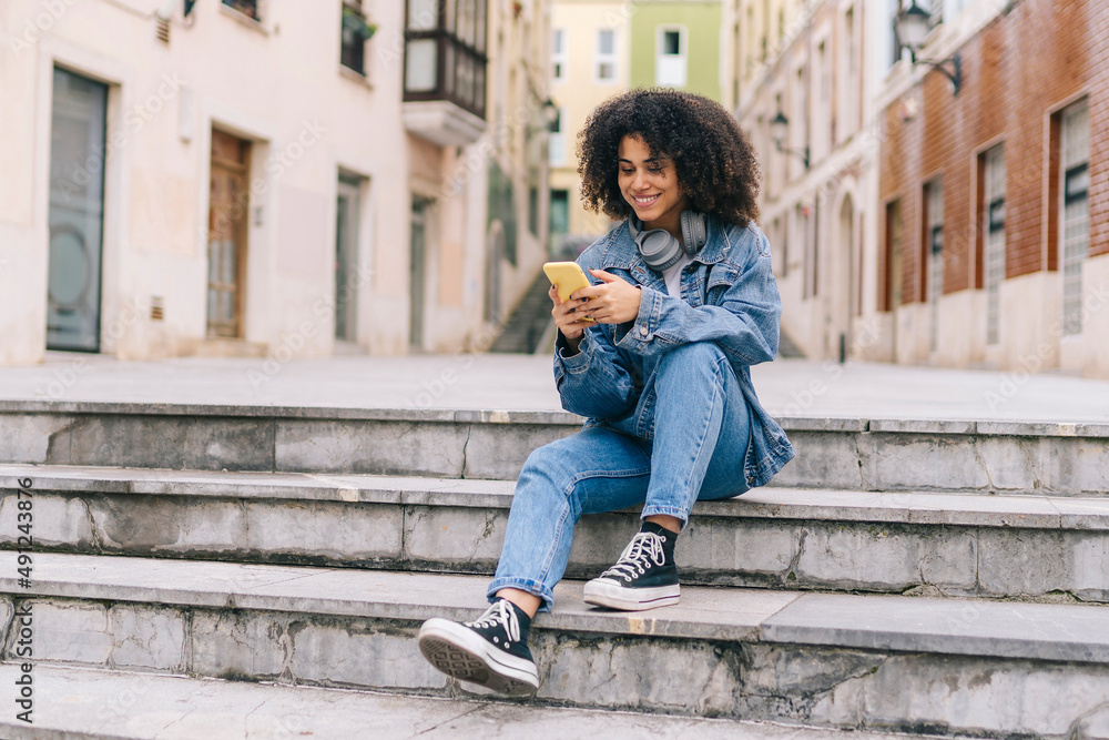 Smiling young woman using mobile phone on staircase Smiling young woman using mobile phone on staircase