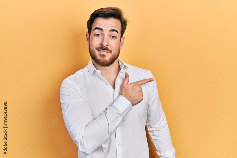 Handsome caucasian man with beard wearing business white shirt smiling cheerful pointing with hand and finger up to the side Handsome caucasian man with beard wearing business white shirt smiling cheerful pointing with hand and finger up to the side