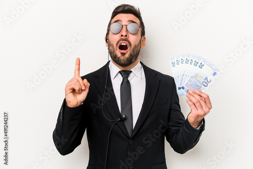 Young caucasian bodyguard man holding banknotes isolated on white background pointing upside with opened mouth.