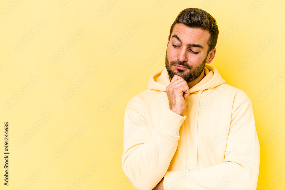 Young caucasian man isolated on yellow background looking sideways with doubtful and skeptical expression. Young caucasian man isolated on yellow background looking sideways with doubtful and skeptical expression.