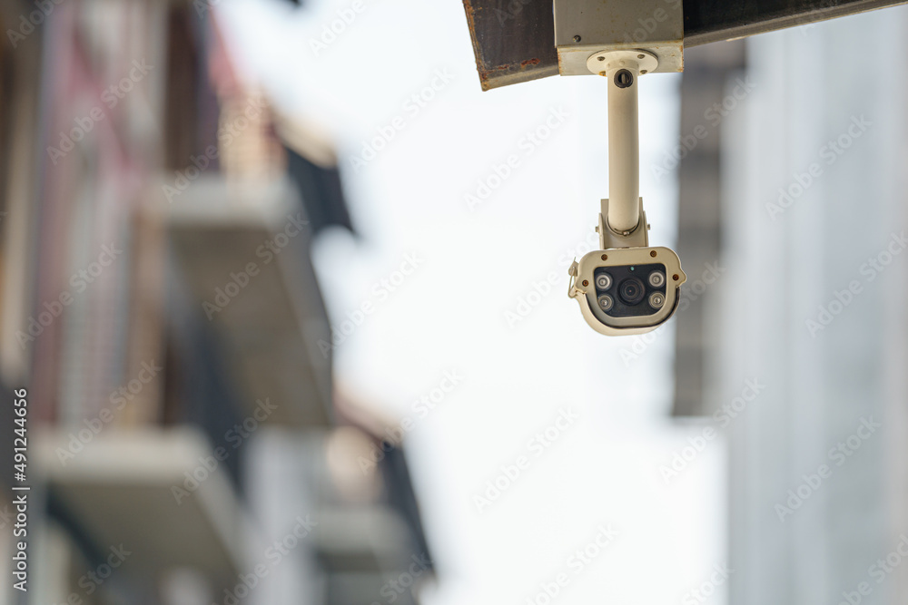 CCTV surveillance security camera on a black pole with blue sky background..