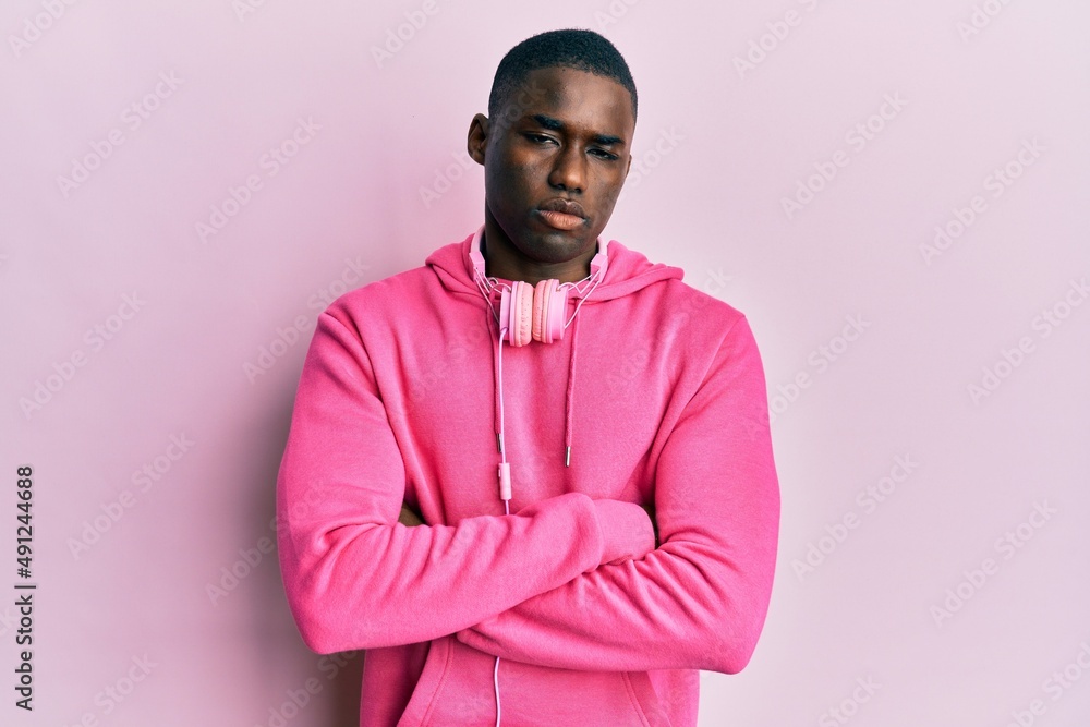 Obraz premium Young african american man wearing gym clothes and using headphones skeptic and nervous, disapproving expression on face with crossed arms. negative person.