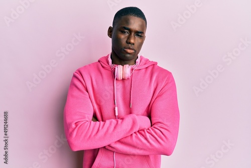 Young african american man wearing gym clothes and using headphones skeptic and nervous, disapproving expression on face with crossed arms. negative person. © Krakenimages.com
