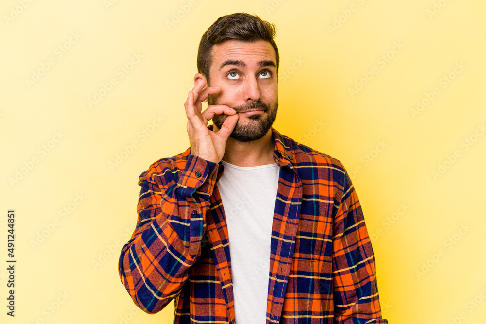 Young caucasian man isolated on yellow background with fingers on lips keeping a secret. Young caucasian man isolated on yellow background with fingers on lips keeping a secret.