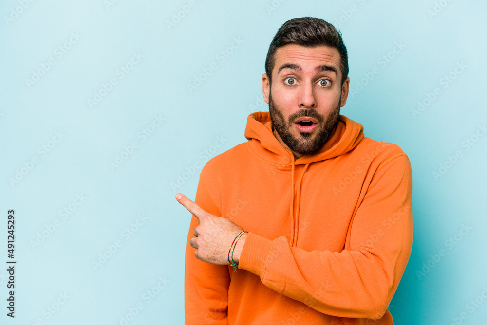 Young caucasian man isolated on blue background pointing to the side Young caucasian man isolated on blue background pointing to the side