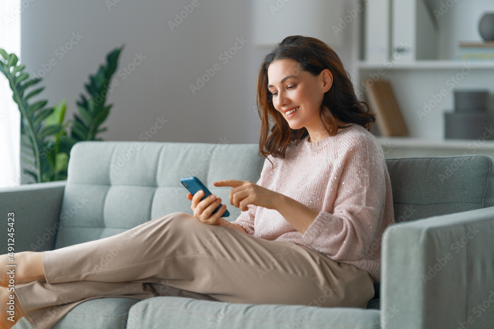 woman is using a phone sitting on a sofa woman is using a phone sitting on a sofa