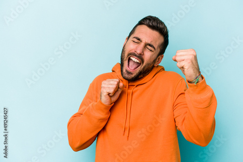 Young caucasian man isolated on blue background dancing and having fun.