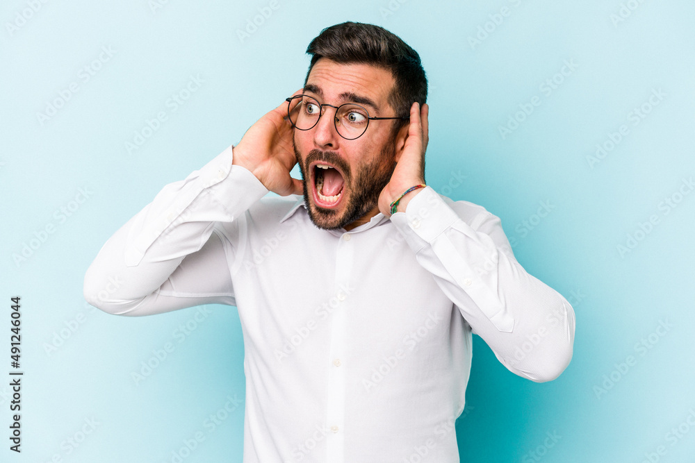 Young caucasian man isolated on blue background screaming, very excited, passionate, satisfied with something. Young caucasian man isolated on blue background screaming, very excited, passionate, satisfied with something.