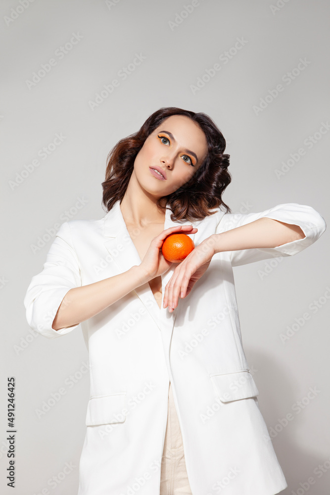 Woman holding tangerine standing against white background Woman holding tangerine standing against white background