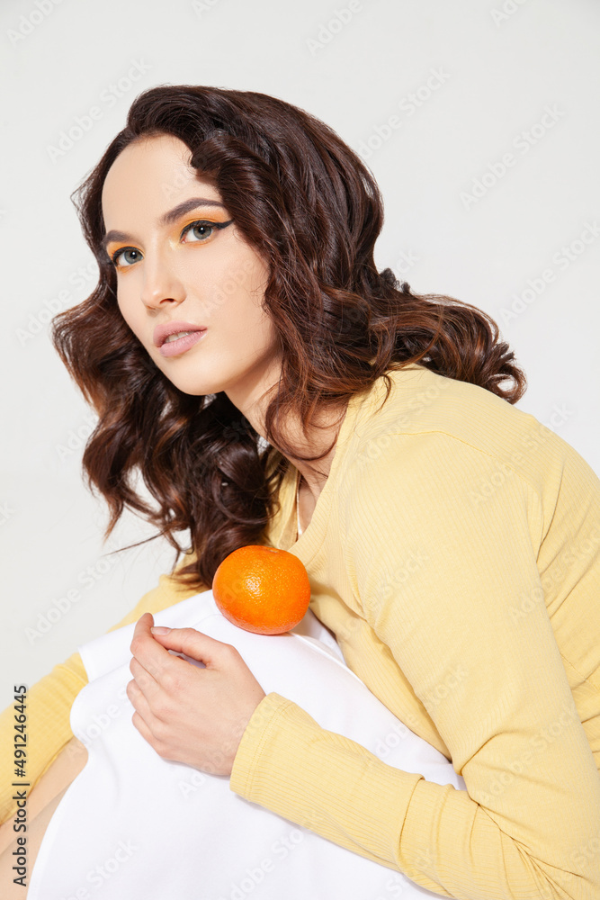 Young woman balancing tangerine on knee at studio Young woman balancing tangerine on knee at studio