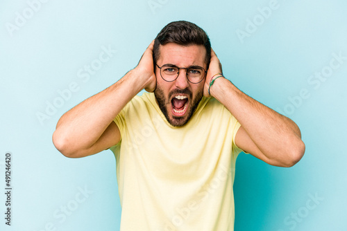 Young caucasian man isolated on blue background screaming, very excited, passionate, satisfied with something.